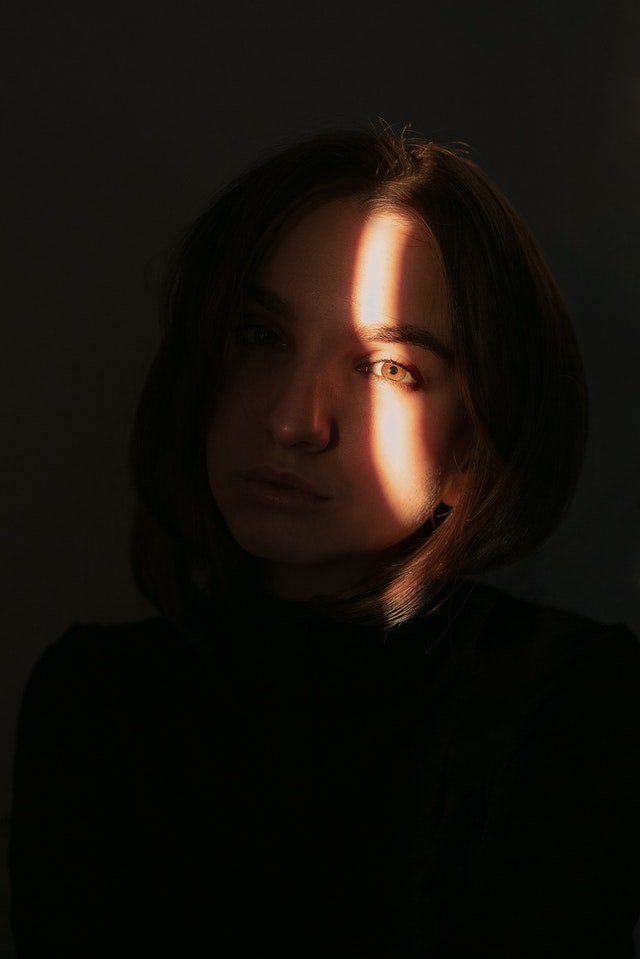 Jeune femme dans l'ombre, la lumière est mise sur son œil.