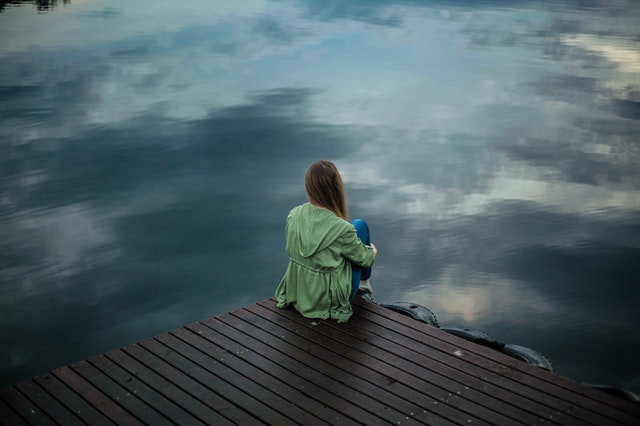 Jeune femme assise au bord de l'eau triste.
